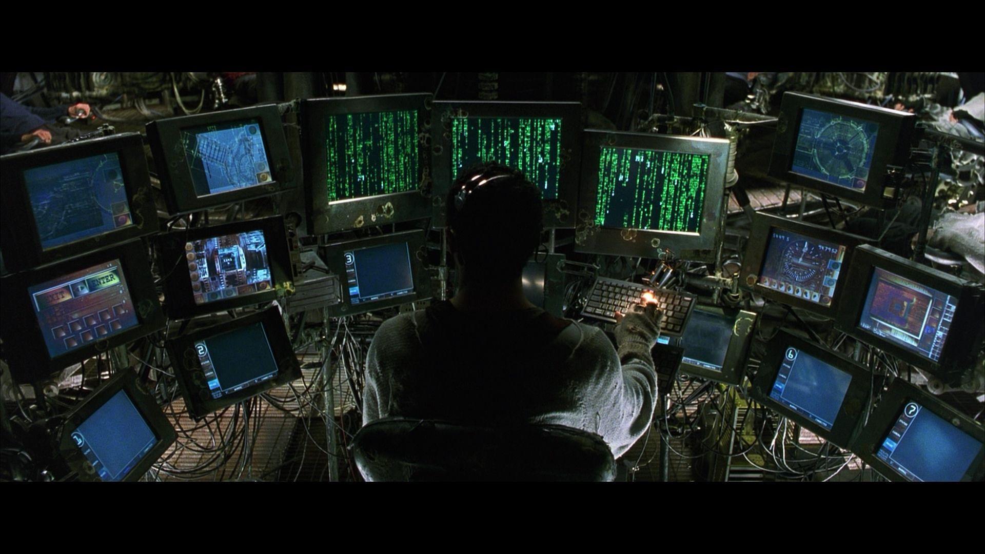 A screenshot from the film The Matrix showing computer monitors covered in code.