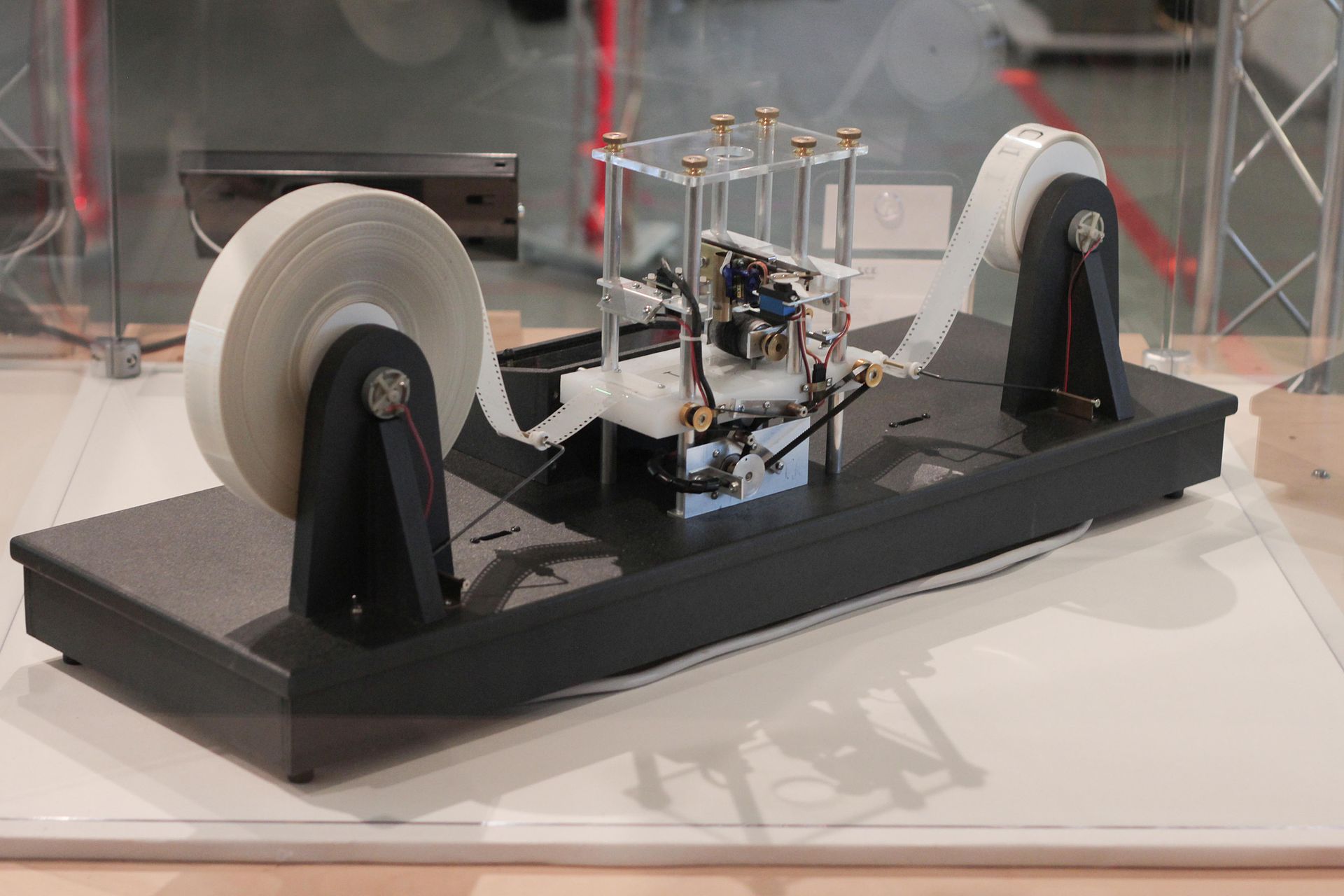 A physical model of a turing machine. There is a tape on two motorised reels. Between the reels is a device that can read and write to the tape